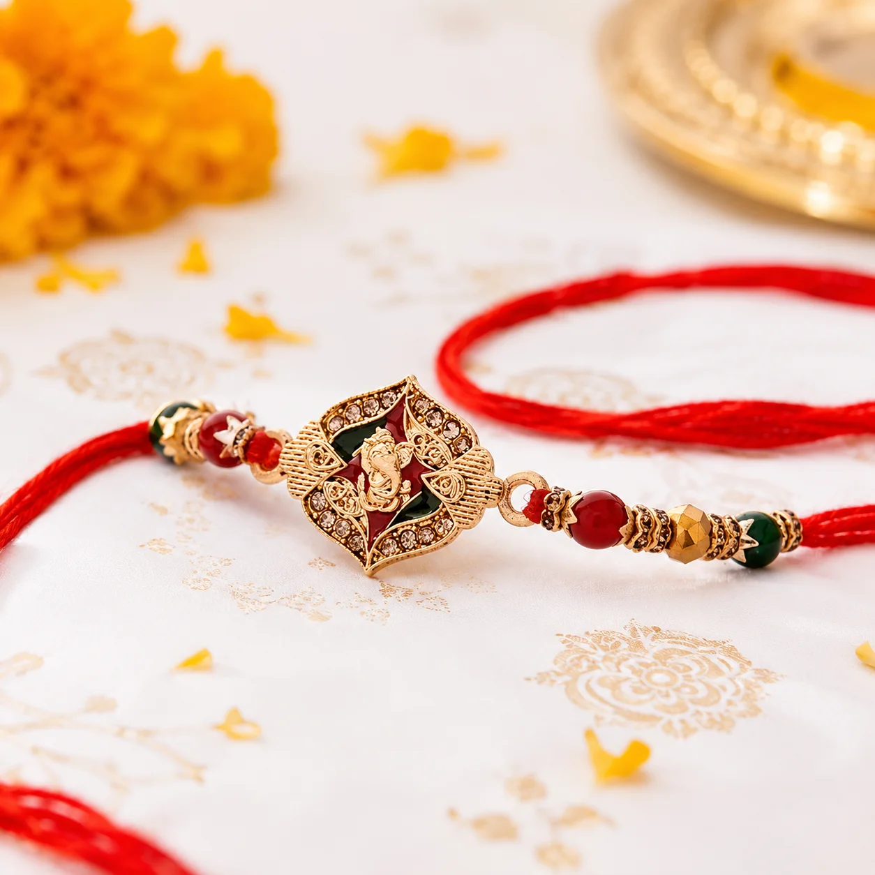 Designer Ganesha Rakhi with sparkling crystal stones, decorative beads, and traditional red thread for Raksha Bandhan