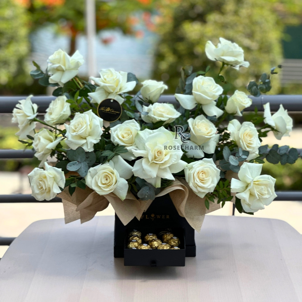 Arrangement of white roses and chocolates in a box