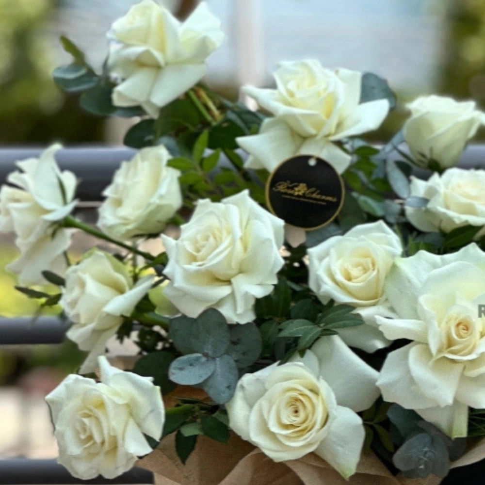 Arrangement of white roses and chocolates in a box
